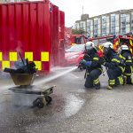 Brandkadetter øver sig på at slukke en lille brand med brandslange