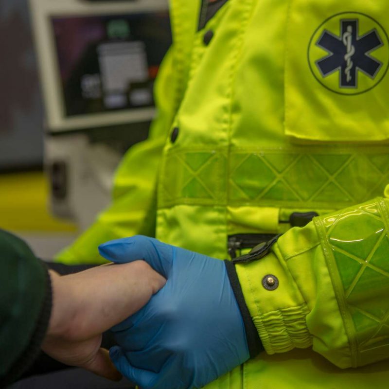 Billede af ambulanceredders hænder der holder en patient i hånden